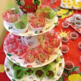 Imagem de várias bandejas de doces, sobre uma mesa colorida.