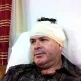 Imagem de David, um homem de 44 anos, deitado na cama hospitalar, com a cabeça alta e um curativo em forma de turbante protegendo a cabeça, ao redor das orelhas.