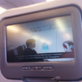 Imagem da tela individual da poltrona do avião da Avianca, com video de instruções de segurança legendado em português e inglês.