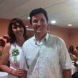 Imagem do Mauro, candidato ao implante coclear, juntamente com sua esposa. Ambos tem mais de 30 anos, estão sorrindo para a câmera e vestem roupas de cores claras.